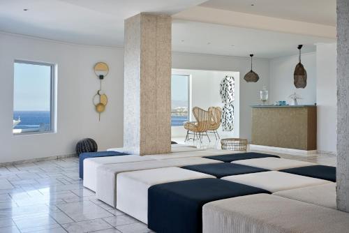 a room with a bed, table, chairs and a window at Kouros Hotel & Suites in Mikonos