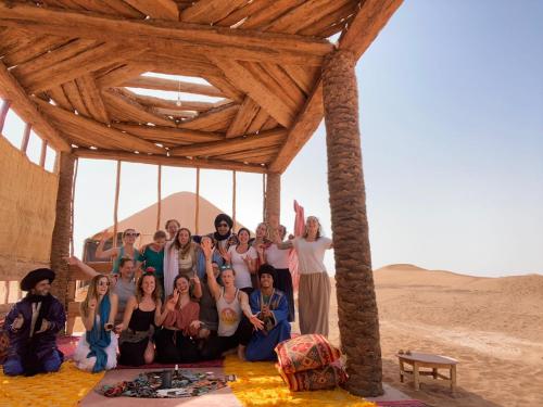 a group of people posing for a picture in the desert at Aladdin Desert Lodge - Mhamid Sahara Camp in El Gouera