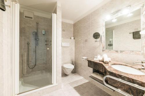 a bathroom with a shower and a sink and a toilet at Hotel Weingarten in Appiano sulla Strada del Vino