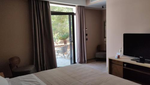 a bedroom with a bed and a television and a sliding glass door at Araja Villa&Suite by Geocharme in San Vito lo Capo