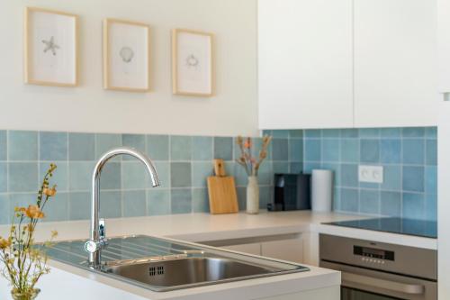 a kitchen with a stainless steel sink and blue tiles at Moderne studio met fantastisch frontaal zeezicht in Nieuwpoort