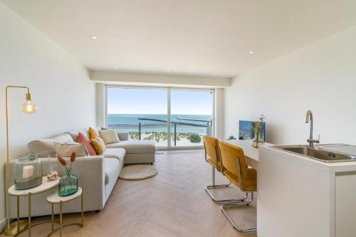 a kitchen and living room with a couch and a sink at Moderne studio met fantastisch frontaal zeezicht in Nieuwpoort