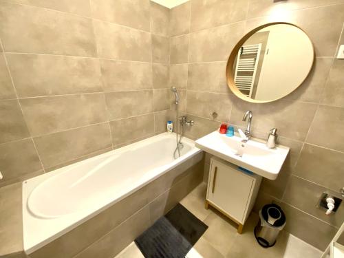 ein Badezimmer mit einer Badewanne, einem Waschbecken und einem Spiegel in der Unterkunft Apartman 001 in Bük