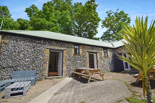 a stone cottage with a picnic table and benches at 5 Bed Barn Conversion - with private hot tub in Birchington