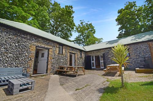 a stone cottage with a bench and a picnic table at 5 Bed Barn Conversion - with private hot tub in Birchington