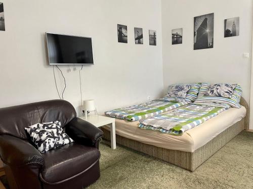 a bedroom with a bed and a chair and a tv at Rudolf House in Budapest