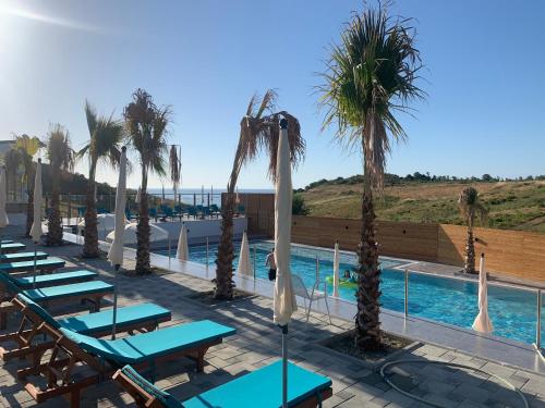 a swimming pool with lounge chairs and palm trees at Saint Michelle Residence in Shetaj