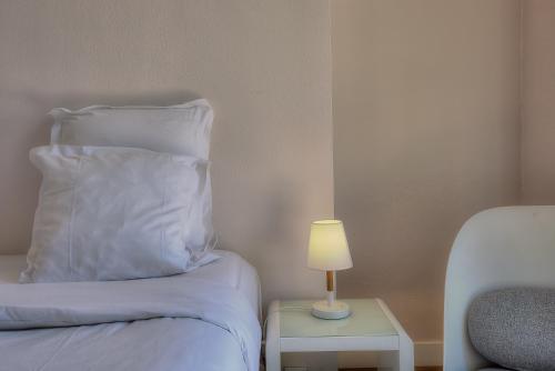 a bed with a white pillow and a lamp on a table at Maison Lamartine - Nice in Nice