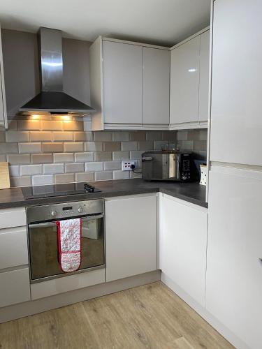 a kitchen with white cabinets and a stove top oven at Chase Bungalow in Billericay
