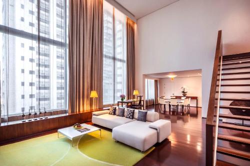 a living room with a white couch and large windows at COMO Metropolitan Bangkok in Bangkok