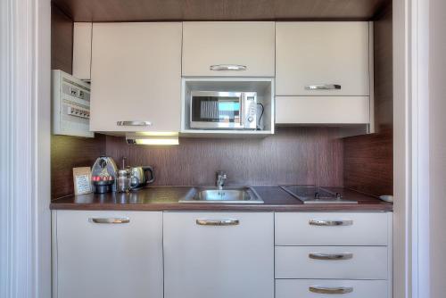 a kitchen with white cabinets and a sink and a microwave at Maison Lamartine - Nice in Nice