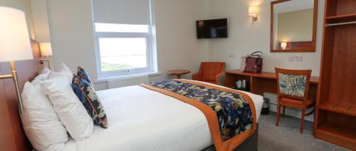a bedroom with a bed and a desk and a window at The Beaches Hotel and Spa in Prestatyn