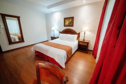 a hotel room with a bed and red curtains at Grand Victoria Boutique Hotel in Loja