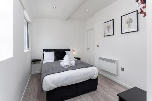 a white bedroom with a large bed with white pillows at Air Host and Stay - Beautiful modern Rodney Street apartment in Liverpool