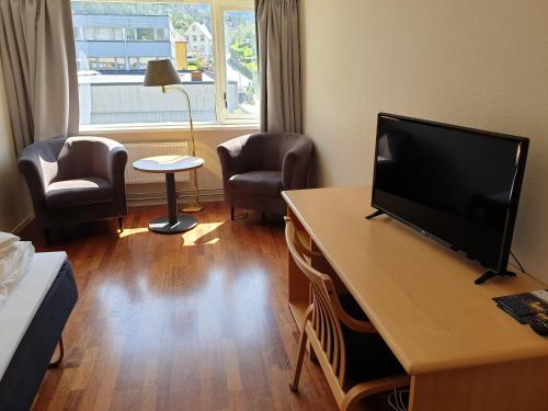 a room with a television on a table with two chairs at Bremanger Fjord Hotell in Svelgen