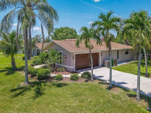 una casa con palmeras delante en Waterfront Pool Villa with Sailboat access en Cape Coral