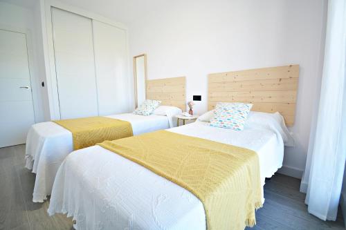 1 dormitorio con 2 camas con sábanas blancas y amarillas en Impresionante apartamento con piscina en Sanxenxo, en Sanxenxo