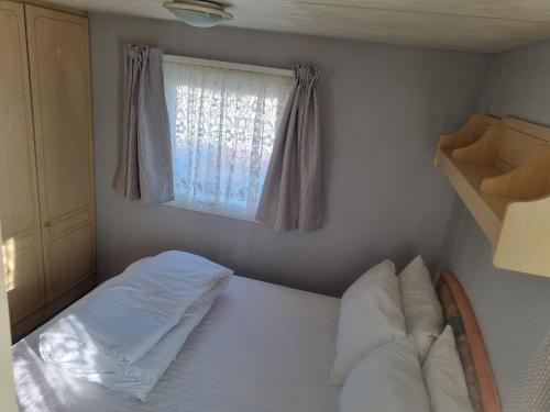 a small bedroom with a bed and a window at TP63 on the Golden Palm Chapel St Leonards in Chapel Saint Leonards