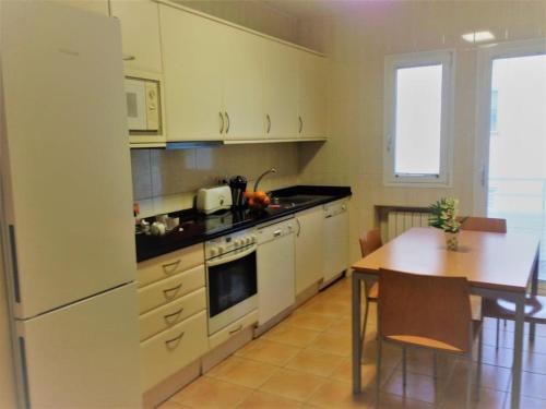 a kitchen with white appliances and a table and a dining room at ÁTICO CENTRO LOGROÑO VISTAS y garaje in Logroño