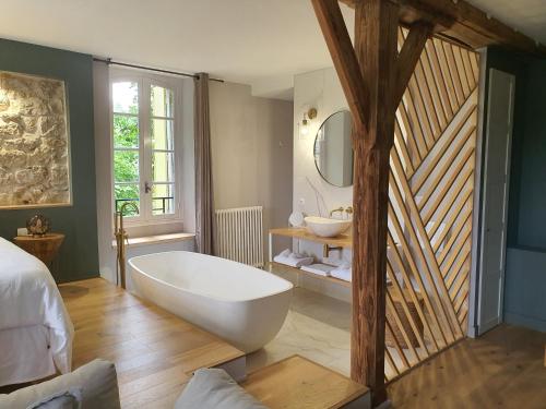 een grote badkamer met een bad en een wastafel bij LE MOULIN DE SALAZAR in Montbarla