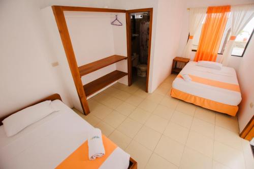 a small room with two beds and a desk at Hostal Sueños Silvestres in Puerto Ayora