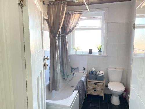 a bathroom with a tub and a toilet and a window at Entire holiday home in Blackpool with free parking and a private patio garden in Blackpool