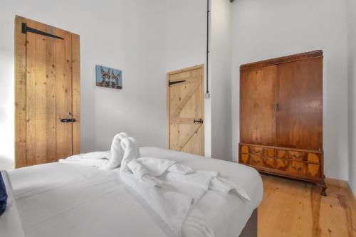 Cama blanca en habitación con puertas de madera en The Flint Barn at Quex Park Estate, en Birchington