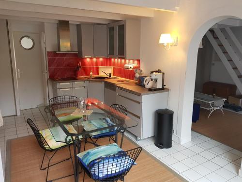 uma cozinha com uma mesa e cadeiras numa cozinha em A 100m de la plage, Aperçu mer, wifi, 2 chambres, 2 salles de bains, 2WC em Saint-Georges-de-Didonne