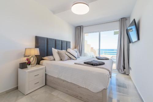 ein Schlafzimmer mit einem großen Bett mit einem großen Fenster in der Unterkunft MalagaSuite Casa Oceano in Mijas Costa