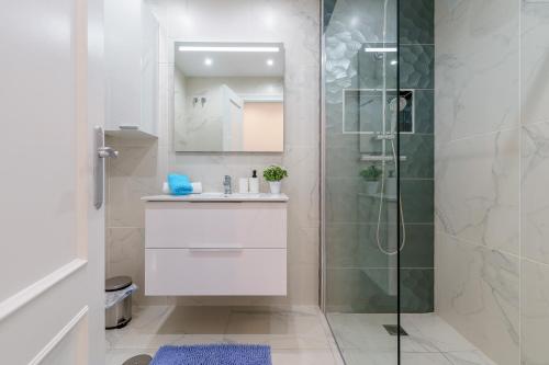 ein weißes Badezimmer mit Dusche und Waschbecken in der Unterkunft MalagaSuite Casa Oceano in Mijas Costa