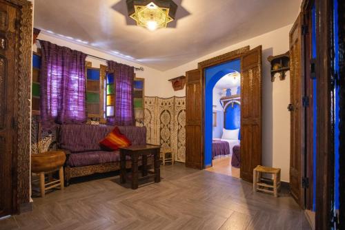 a living room with a purple couch and a bedroom at Casa La Hiba in Chefchaouene