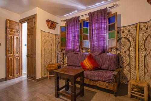 a living room with a purple couch and a table at Casa La Hiba in Chefchaouene