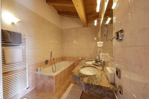 a bathroom with a sink and a bath tub at Hotel Weingarten in Appiano sulla Strada del Vino