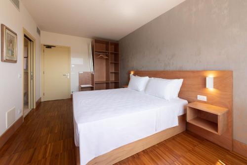 a bedroom with a large white bed and wooden floors at Torre Antica Venice Airport Hotel in Tessera