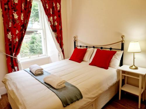 a bedroom with a bed with red pillows and a window at Georgian 2 Bedroom Apartment in Edinburgh