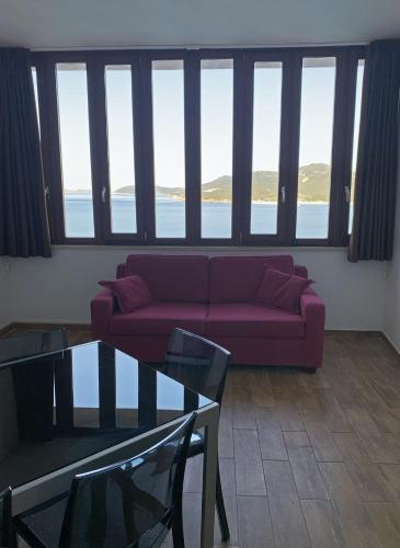 a living room with a red couch in front of windows at Nuraghe Apartments in Teulada
