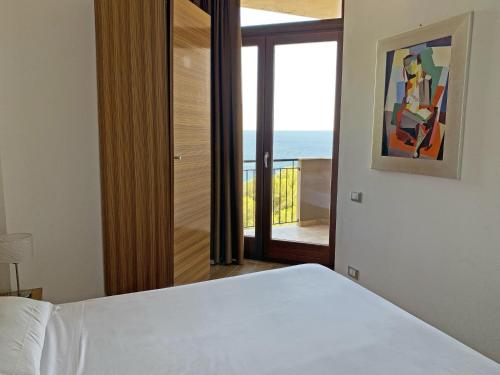 a bedroom with a bed and a view of the ocean at Nuraghe Apartments in Teulada