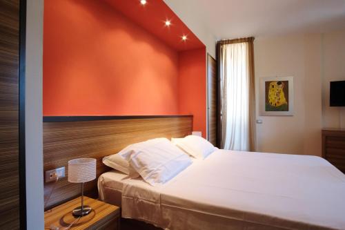a bedroom with a bed with an orange wall at Nuraghe Apartments in Teulada