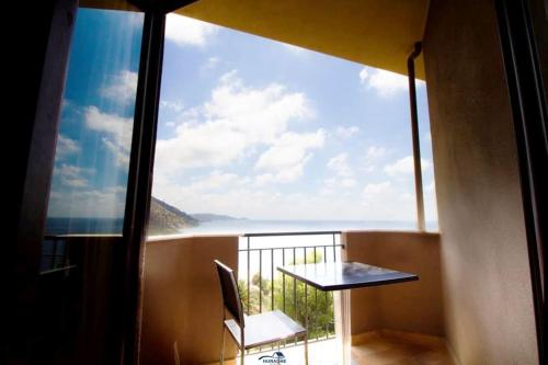 a balcony with a table and a view of the ocean at Nuraghe Apartments in Teulada