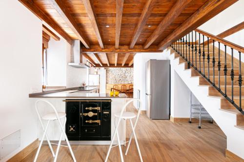 a kitchen with white walls and wooden ceilings at La casita de susa en mazcuerras in Villanueva de la Peña