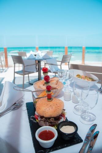 a table with a sandwich on a table with the beach at Vincci Dar Midoun in Djerba