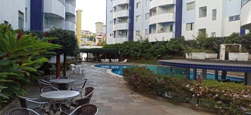 a patio with tables and chairs next to a swimming pool at Apart no Águas da Serra - 115B in Rio Quente