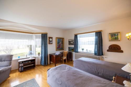 a bedroom with two beds and a desk and a window at Heidi Guesthouse in Selfoss