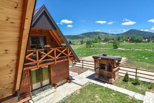 a wooden house with a grill next to a field at Big bear villas in Žabljak