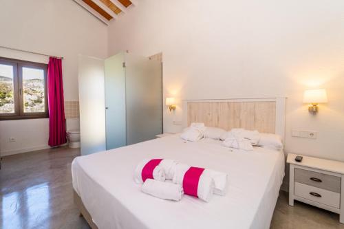 1 dormitorio con 1 cama blanca grande y toallas rojas y blancas en Hostal Foies de Baix, en Relleu