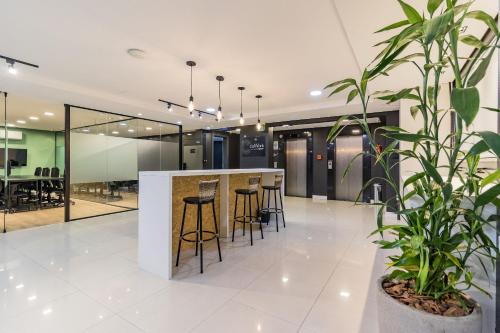 a lobby with a bar with stools and plants at Century Park by My Way in Porto Alegre