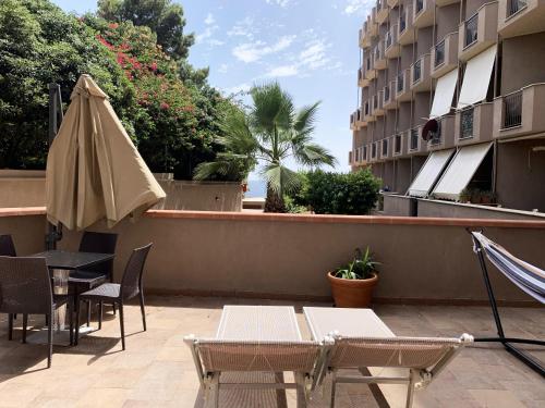 patio ze stołem, parasolem i krzesłami w obiekcie Nuraghe Apartments w mieście Teulada