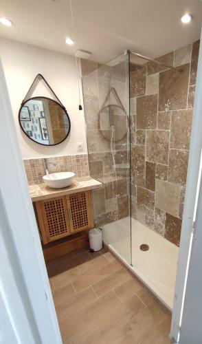 une salle de bain avec une douche avec un lavabo et un miroir dans l'établissement Maison de la plage, à Pirou