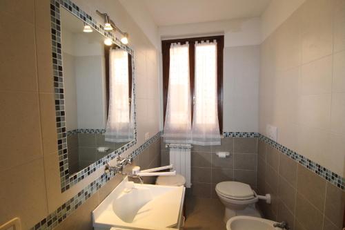 ein Badezimmer mit einem Waschbecken, einem WC und einem Spiegel in der Unterkunft Bellavista apartment 20 minutes from sea/beaches in Giuncarico