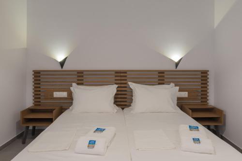 two beds in a room with white sheets and pillows at Viva Mare Studios in Astypalaia Town